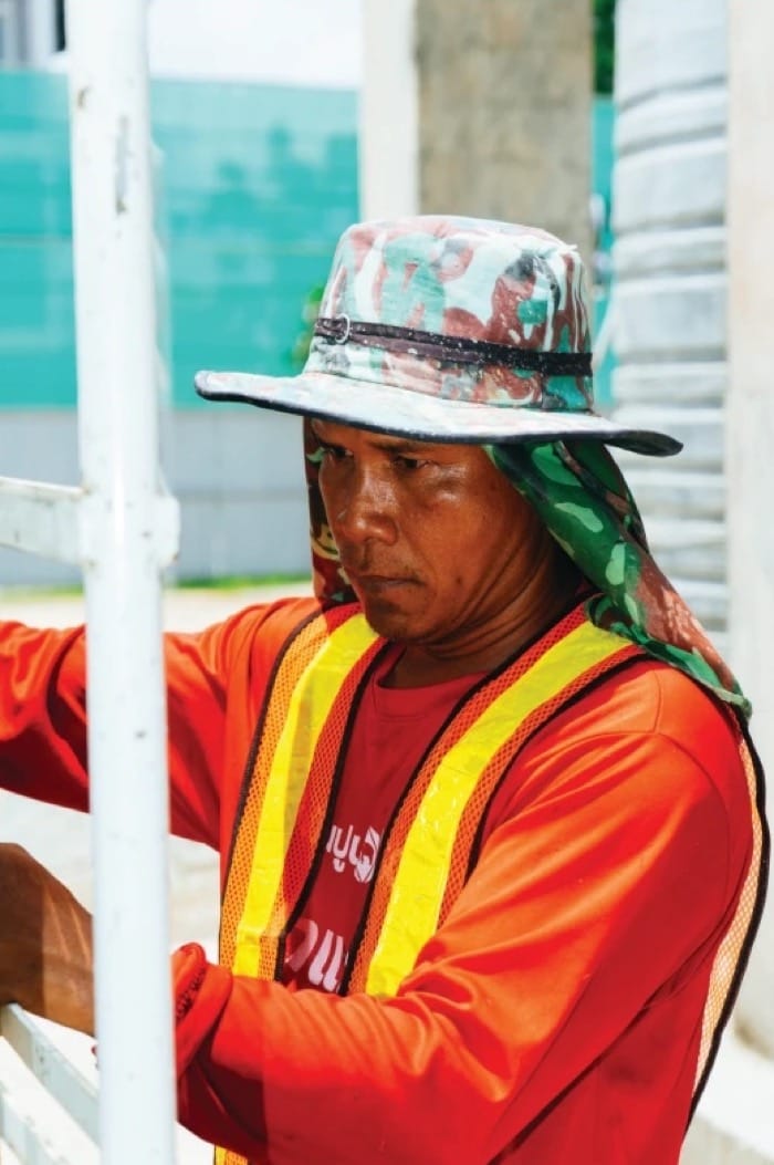 A site worker in a wide-brim hat and hi-vis vest
