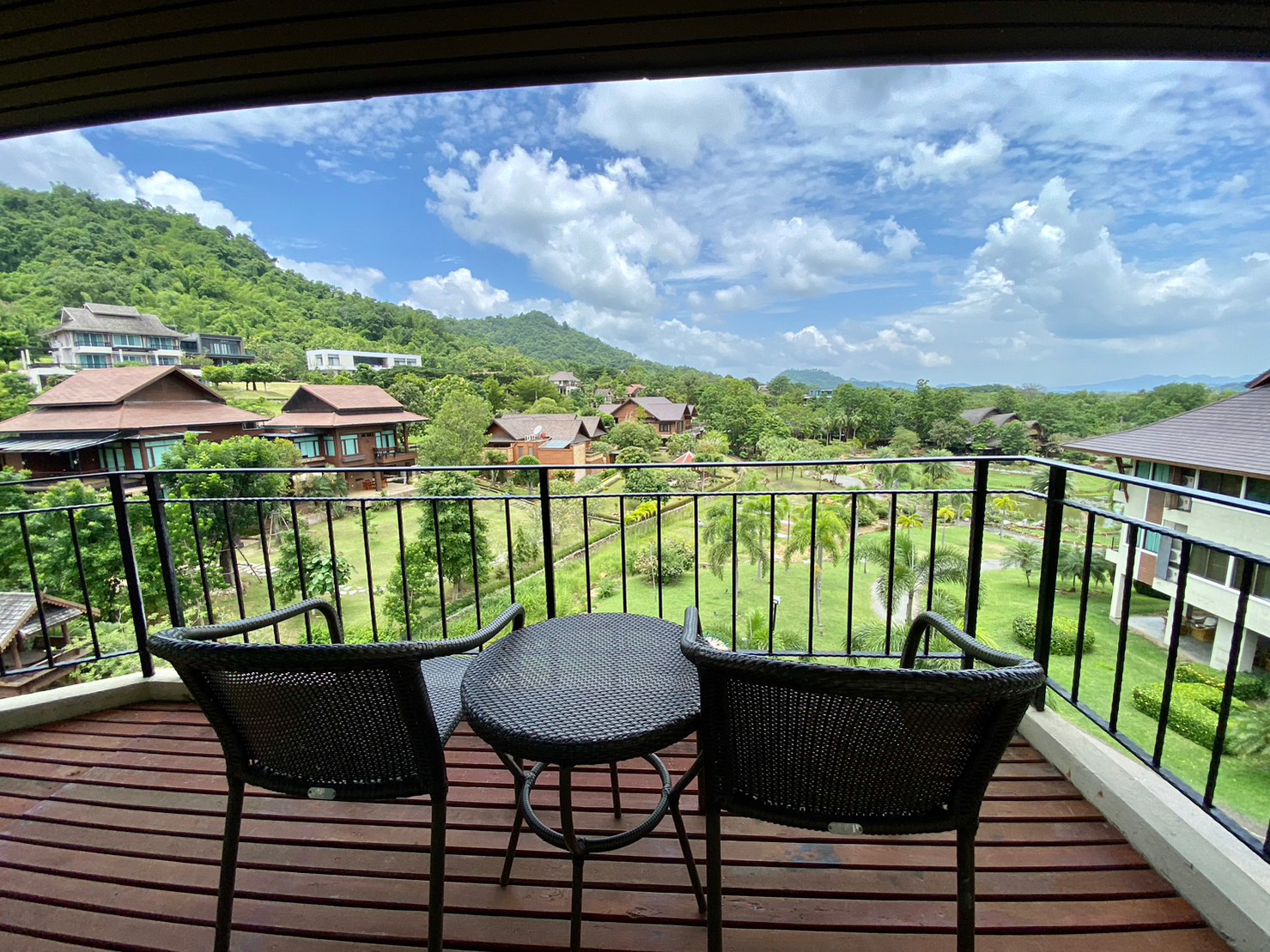 Lawns, palms and garden paths below the hills, seen from a balcony